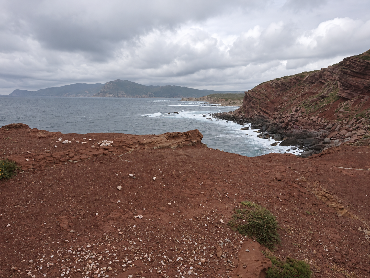 Roter Fels und Brandung an Sardiniens Küste.